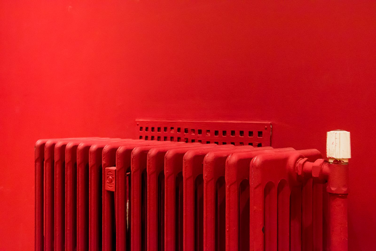 Rode radiator tegen een muur in precies dezelfde kleur