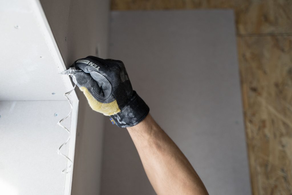 Hand brengt met troffel gladde pleisterlaag aan op wand