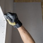 Hand brengt met troffel gladde pleisterlaag aan op wand
