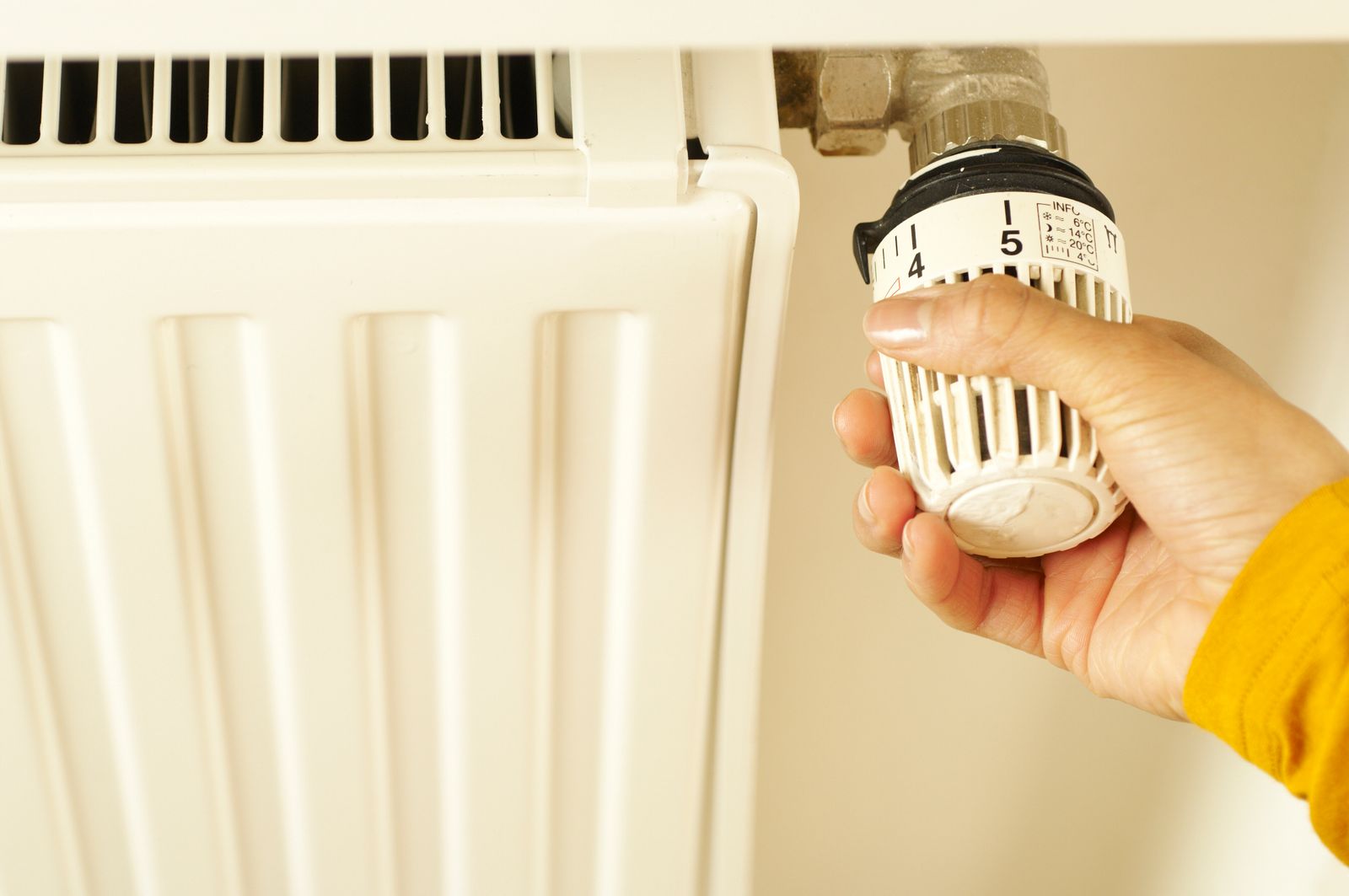 Hand draait de thermostaatknop van een radiator helemaal open