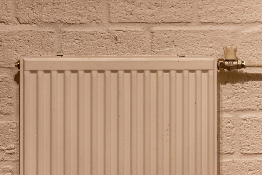 Witte radiator tegen een bakstenen muur in huis