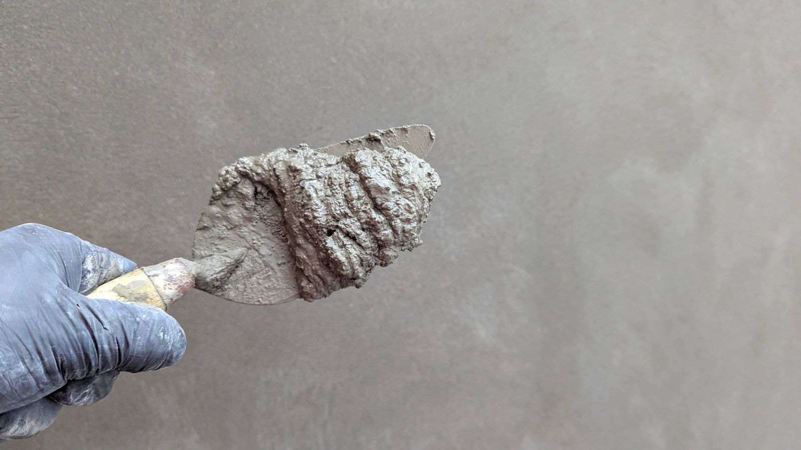 Detailopname van een hand die plamuur aanbrengt met een spaan
