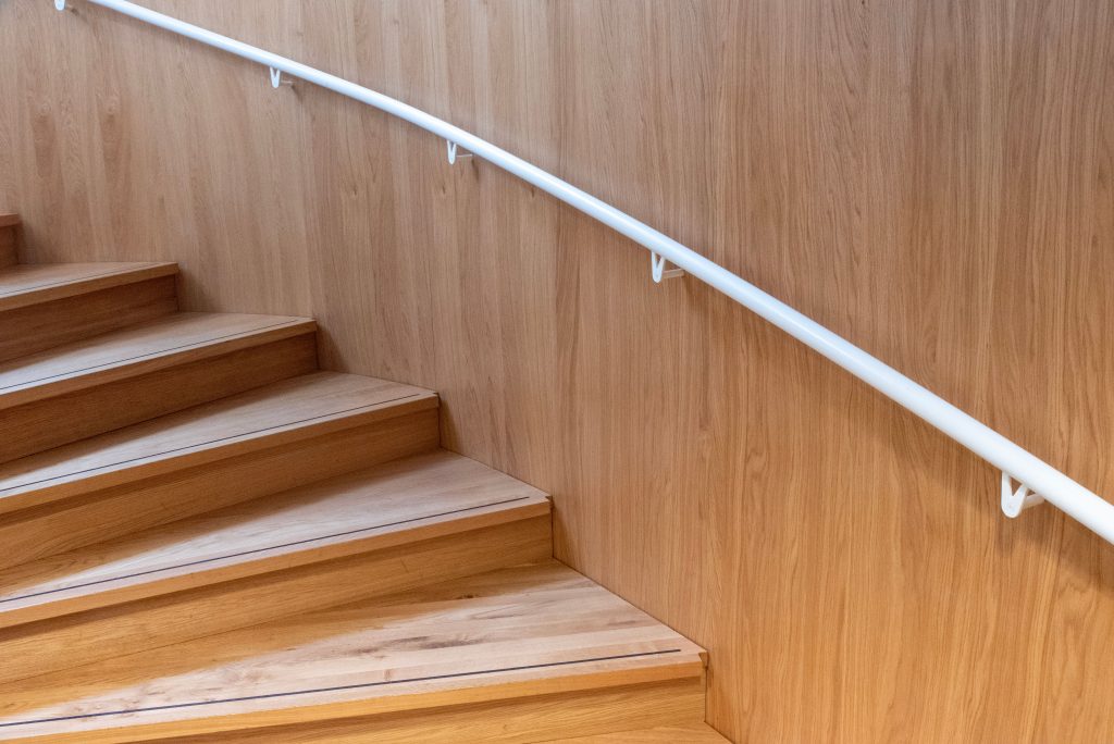 Houten trap met wit geschilderde leuning in een woonhuis