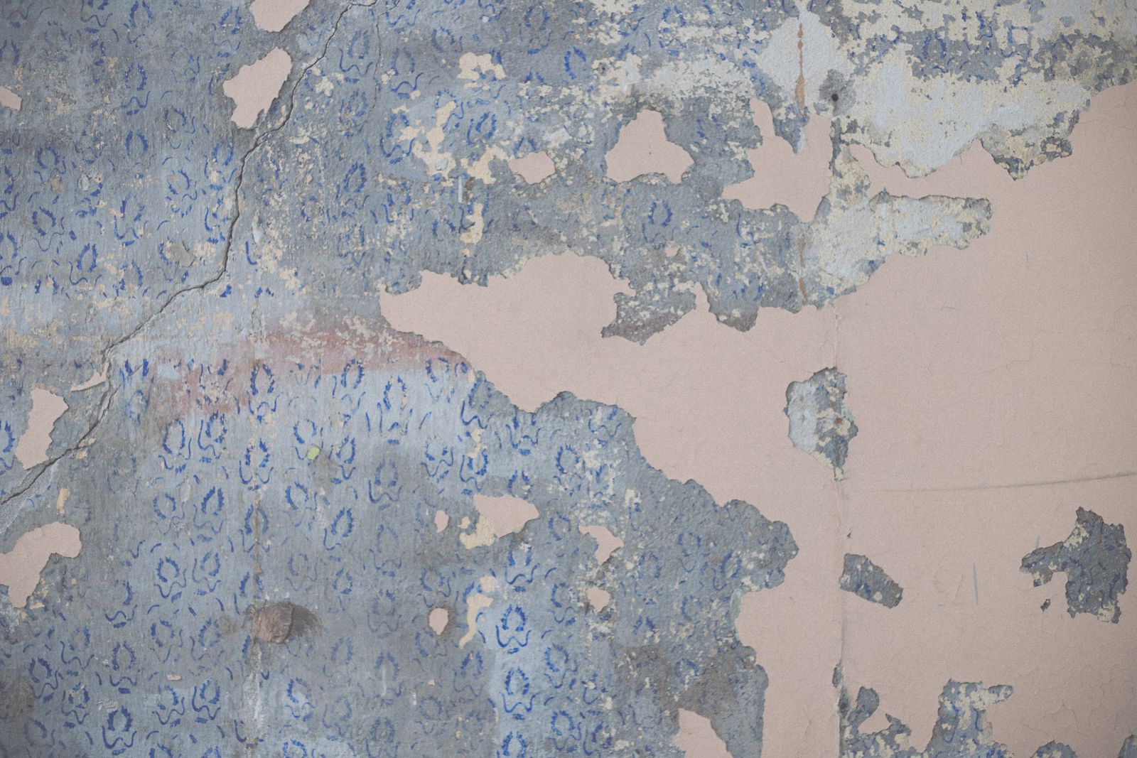 Oud behang met blauwe bloemenprint laat los van de muur