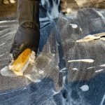 Hand met borstel schrobt de voegen tussen tegels