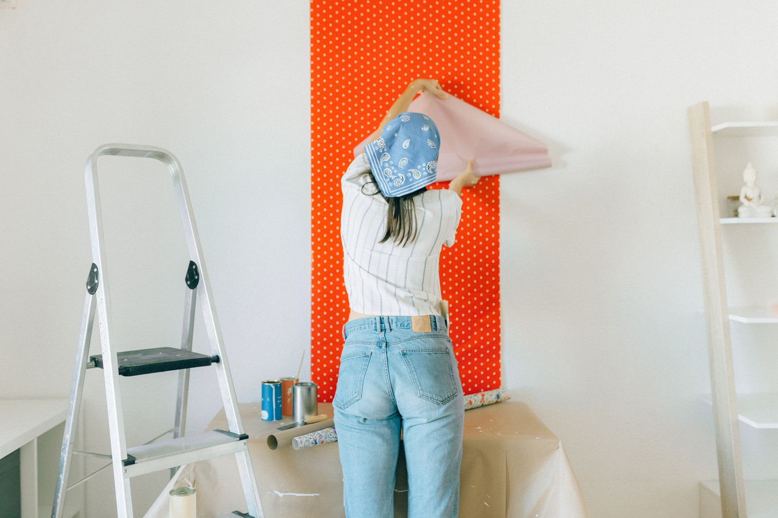 Vrouw brengt behang met stippen aan op de muur