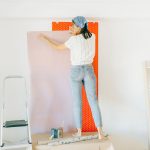 Vrouw brengt vlies-behang aan op een muur tijdens verbouwing