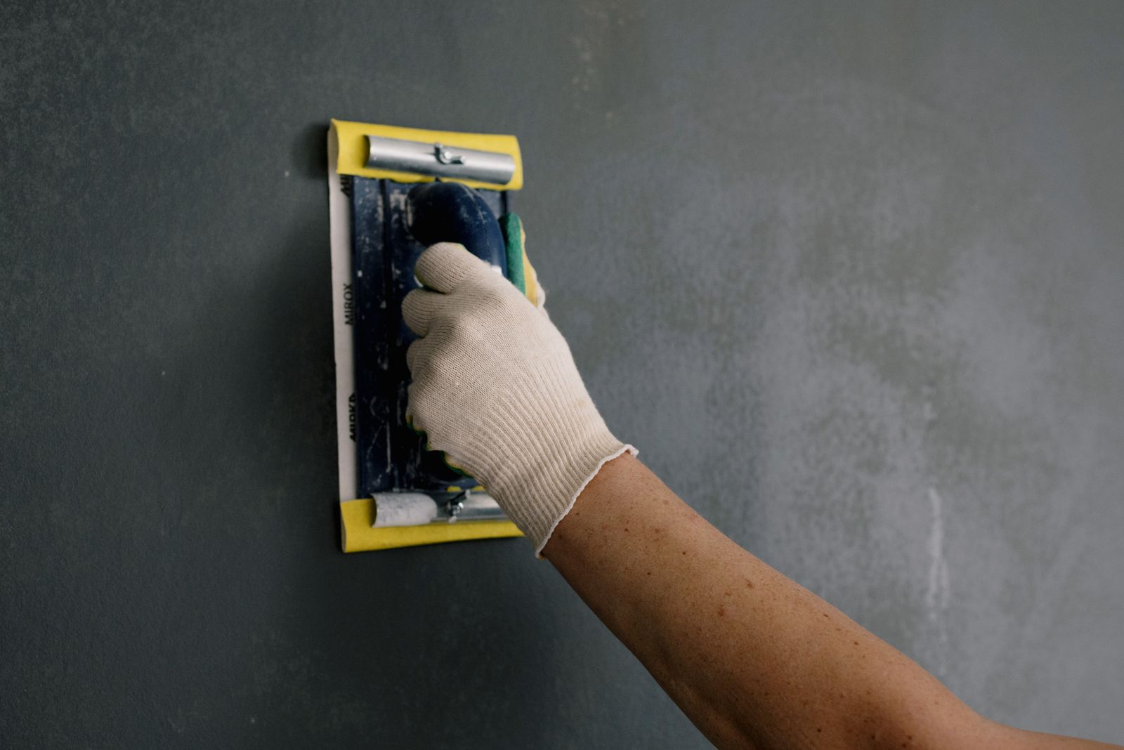 Persoon schraapt met gereedschap loszittend stucwerk van de muur