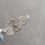 Hand met troffel brengt stucwerk aan op een muur