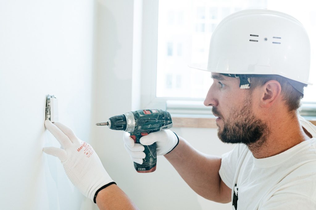 Man boort met een boormachine een gat in de wand