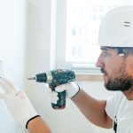 Man boort met een boormachine een gat in de wand