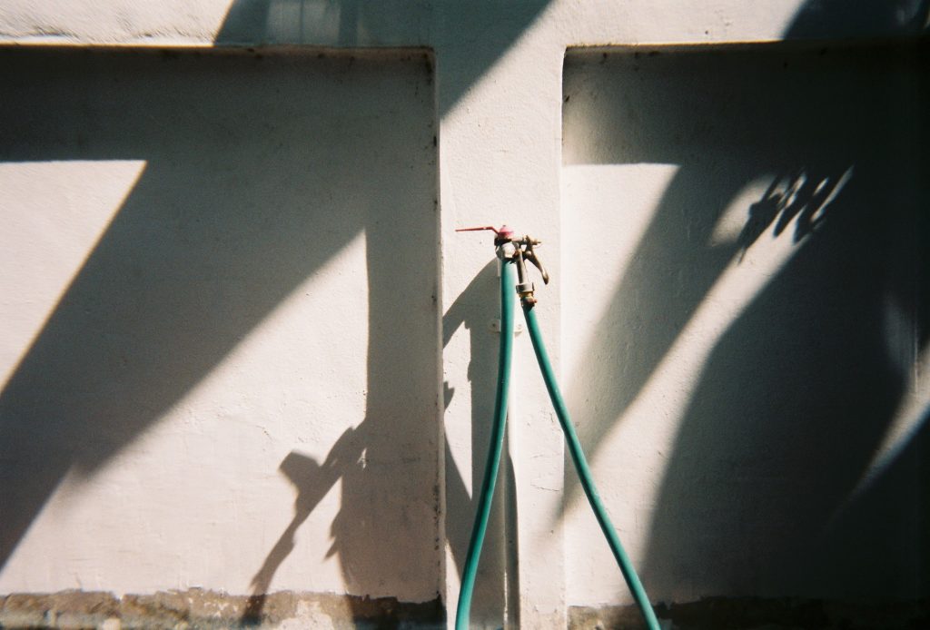 Buitenkraan met tuinslang bevestigd aan een muur in de tuin