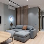 Woonkamer met grijze bank en airco-unit aan de wand