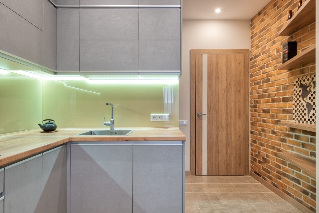 Keuken met bakstenen muur en ledverlichting onder de kastjes